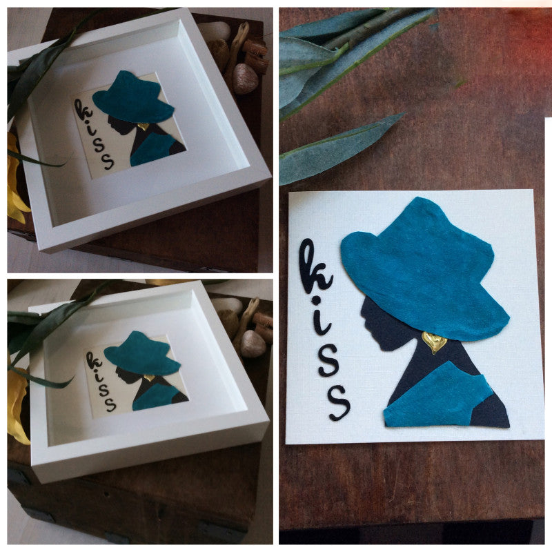Handmade greeting card. Black card silhouette of a lady wearing a turquoise hat and tunic and gold earring. Wording on the card is Kiss