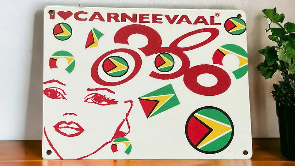 Guyana edition decorative carnival art sign with red illustration and flag motifs styled on wooden surface with houseplant