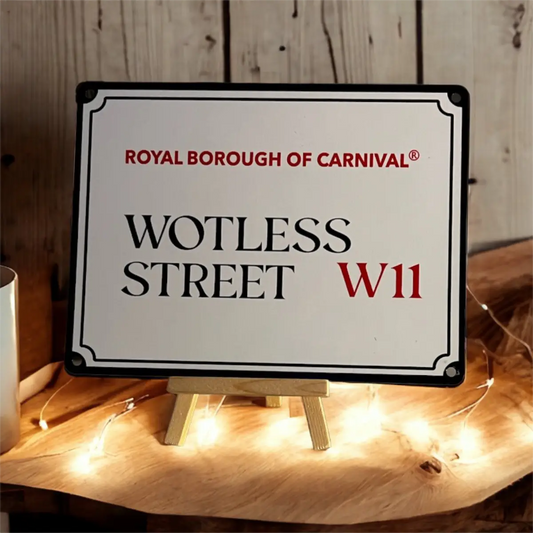 Wotless Street W11 decorative carnival sign styled on a wooden stand illuminated with warm fairy lights